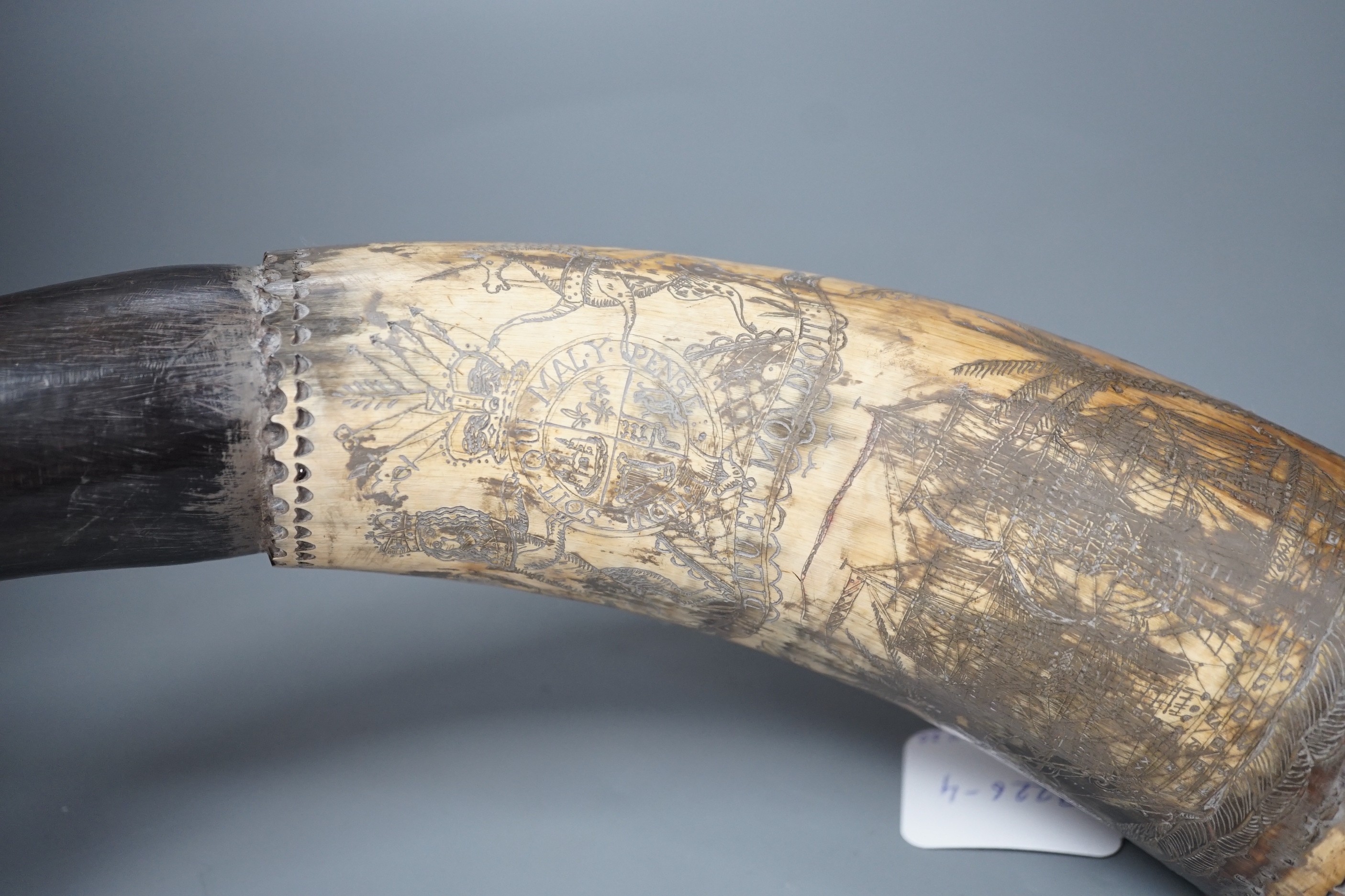 An early 19th century scrimshaw powder horn, ornately engraved with the Royal Coat of Arms, a castle and galleon and an inscription: Amos Mills. 38cms long.